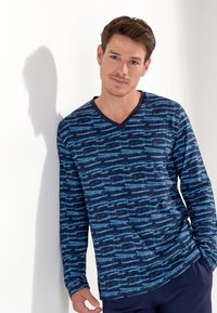 Camicetta a maniche lunghe di colore blu navy con motivi astratti di colore azzurro. Presenta un colletto a V e una texture di tessuto morbido. Ideale per l'abbigliamento informale.