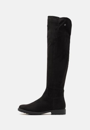 Botas negras por encima de la rodilla hechas de un material similar al ante. Ajuste ceñido con puntera redondeada y suela plana de goma. Diseño minimalista, sin hardware visible.