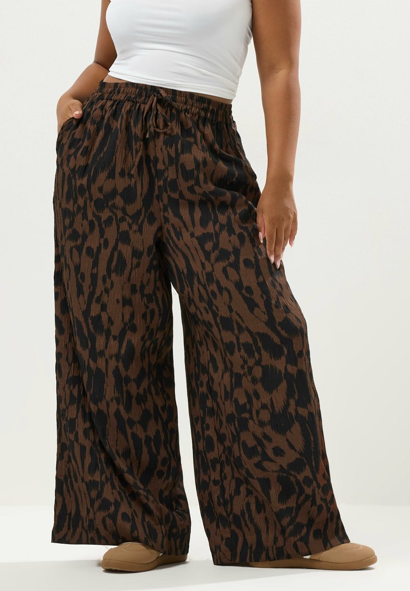 Ruskea ja musta leopardi-printti, leveälahkeiset housut, joissa on joustava vyötärö ja sivutaskut. Pehmeä, teksturoitu kangas mukavuutta varten.