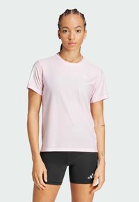 Camiseta deportiva de color rosa claro con cuello redondo y mangas cortas, que presenta un tejido texturizado y detalle de logo blanco en el pecho.