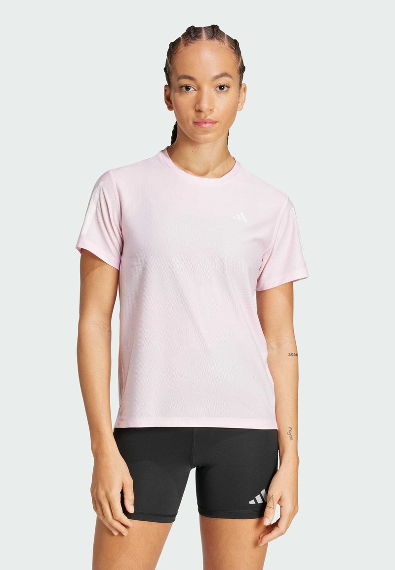 Camiseta deportiva de color rosa claro con cuello redondo y mangas cortas, que presenta un tejido texturizado y detalle de logo blanco en el pecho.