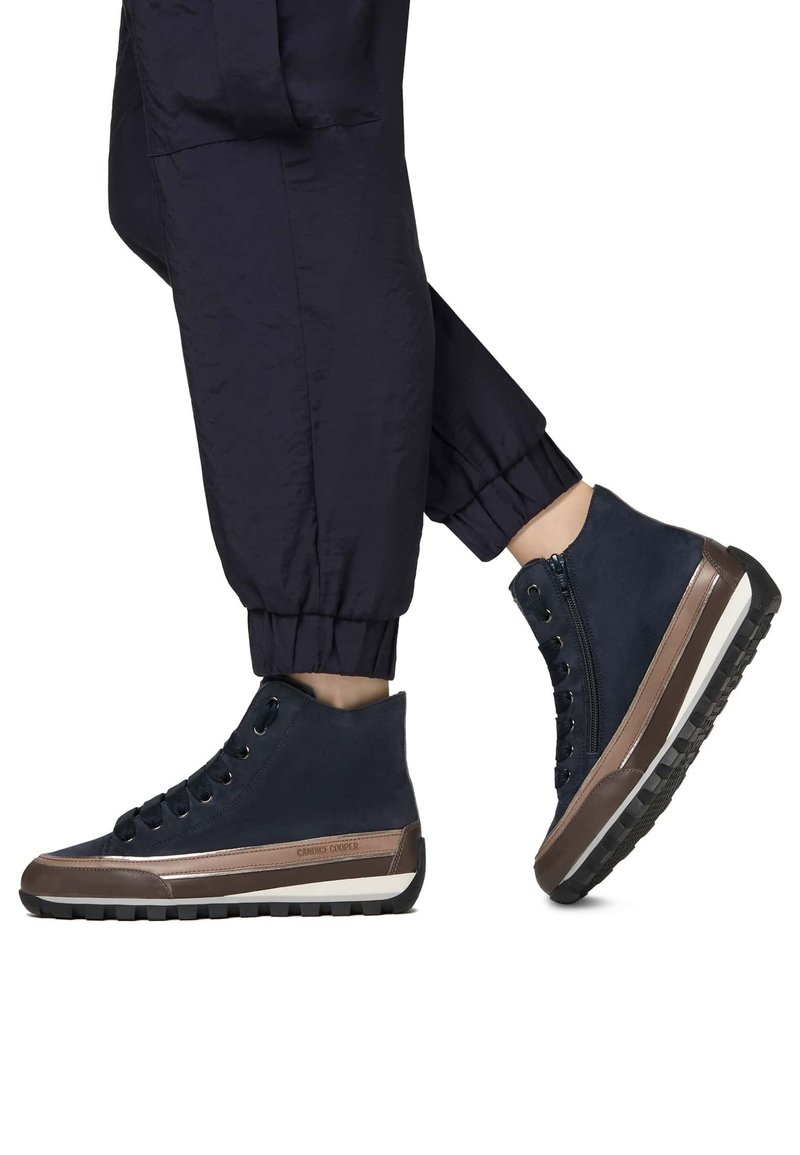 Baskets montantes bleues avec des accents marron, présentant une semelle en caoutchouc, des lacets ronds et un design de cheville zippé.
