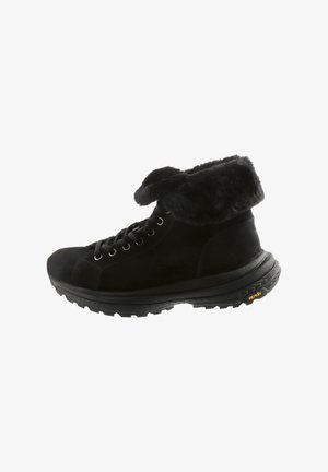 Schwarze Winterstiefel mit Kunstfellkragen, Schnürung auf der Vorderseite und dicker Vibram-Sohle, die für guten Halt im Freien sorgt.