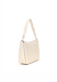 Beżowa skórzana torebka o strukturalnym kształcie; ma płaskie dno, regulowany pasek na ramię oraz subtelne logo z przodu.