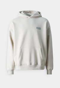 Felpa di colore crema realizzata in tessuto morbido. Presenta una tasca a marsupio, polsini a costine e un piccolo logo blu sul petto.