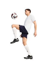 Witte korte mouwen shirt, marineblauwe shorts, witte sokken, zwarte voetbalschoenen. De persoon balanceert een gemarmerde voetbal op hun knie.