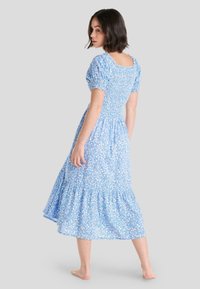 Vestido midi azul con estampado floral, mangas abullonadas, corsé ajustado y falda de volantes. Presenta textura fruncida y escote cuadrado.