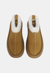 Pantofole in camoscio marrone slip-on con fodera in pelliccia sintetica bianca e suola in gomma liscia, caratterizzate da una cucitura al centro e hardware minimale.