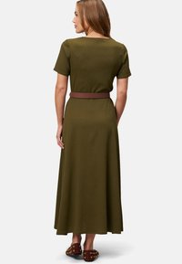 Robe tricotée vert olive avec des manches courtes, dotée d'une ceinture marron à la taille. Texture douce, silhouette en A fluide, longueur cheville.
