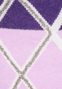 Violetti ja vaaleanpunainen neulottu kangas, jossa on timanttimainen kuvio, jota korostaa rivi pieniä koristehelmiä valkoisten sauma-alueiden varrella.
