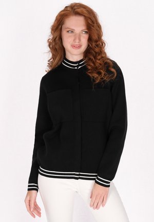 Zwarte cardigan met twee borstzakken, kraag en manchetten in zwart-witte strepen, geribde zoom, zachte stof en een losse pasvorm.