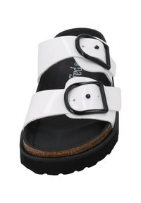 White double-buckle sandal with black hardware, cork footbed, and textured black sole. Features adjustable straps for a customizable fit.