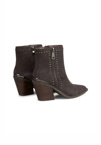 Stivali ankle in suede grigi con punta appuntita, cerniere laterali, dettagli con borchie e un tacco spesso in legno con base metallica.