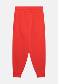 Røde bomulds sweatpants med elastisk talje, tapered ben og ribbede manchetter. Glat tekstur og enkelt design uden yderligere dekorationer.