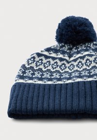 K�ék és fehér kötött téli sapka pom-pommal, bordás mandzsettával és felette mintás designnal.