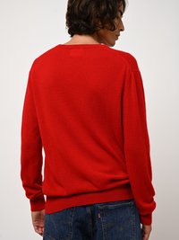 Maglione rosso a collo rotondo realizzato in materiale morbido. Presenta polsini e orlo a costine, con una vestibilità rilassata e un design minimalista.