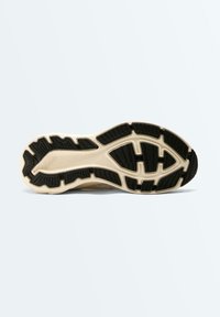 Semelle de chaussure avec base beige et motifs d'adhérence texturés noirs, portant le nom de la marque « OHSKO » embossé près du talon.