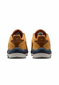 Para brązowo-granatowych sneakersów Nike SB widoczne z tyłu, wykonanych z zamszu i materiałów tekstylnych, z białymi gumowymi podeszwami.