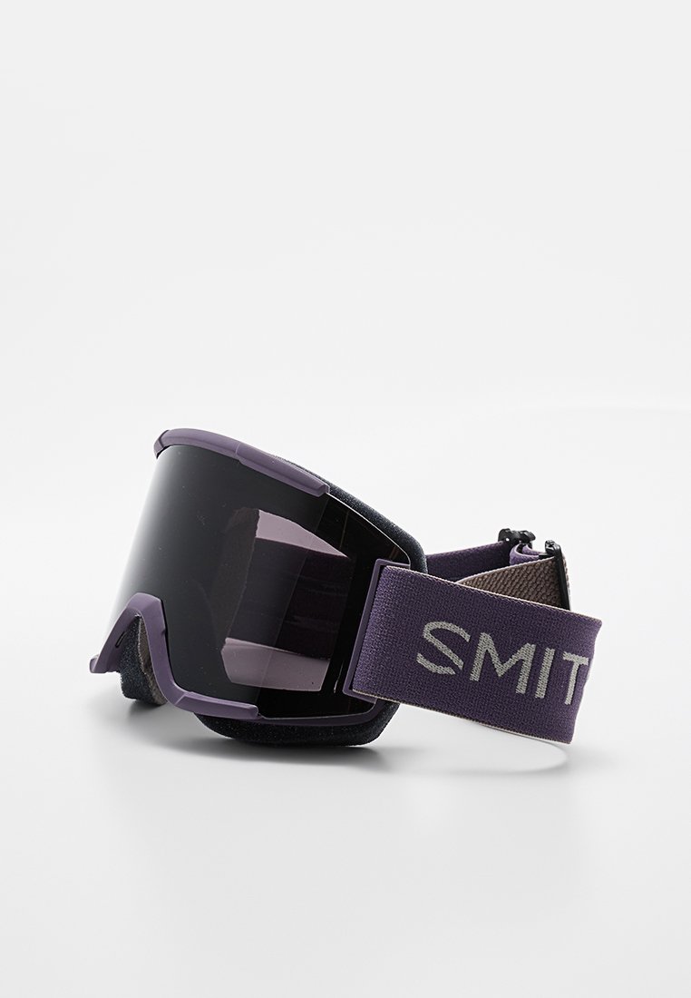 Lila Skibrille mit einem großen dunklen Glas, schwarzem Schaumstoffpolster und einem strukturierten Band mit dem Aufdruck "SMITH". Entworfen für optimale Sicht bei Wintersportarten.