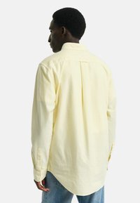 Langsleeve shirt in geel met witte strepen, voorzien van een knoopsluitingkraag en afgeronde zoom, gemaakt van een lichtgewicht stof.