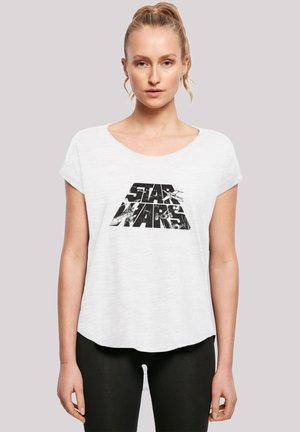 Hvit t-skjorte med korte ermer som har et svart "STAR WARS" logo-trykk. Rund hals og løs passform med bølget kant.