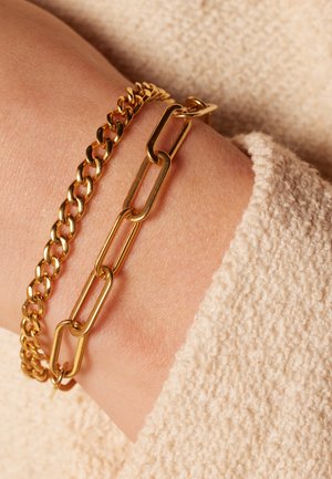 Gouden armbanden met een gladde, ronde kettingontwerp en een grotere schakelketting. Beide zijn metallic en gestructureerd.