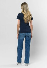 Námornícky pruhovaný top s krátkym rukávom v kombinácii s svetlomodrými rovnými džínsami, obuté s bielymi teniskami. Vlasy padajú v jemných vlnách pozdĺž chrbta.