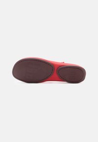 Red shoe sole with a smooth texture, featuring a rounded shape and embossed size '38'. The sole has contrasting brown accents.
