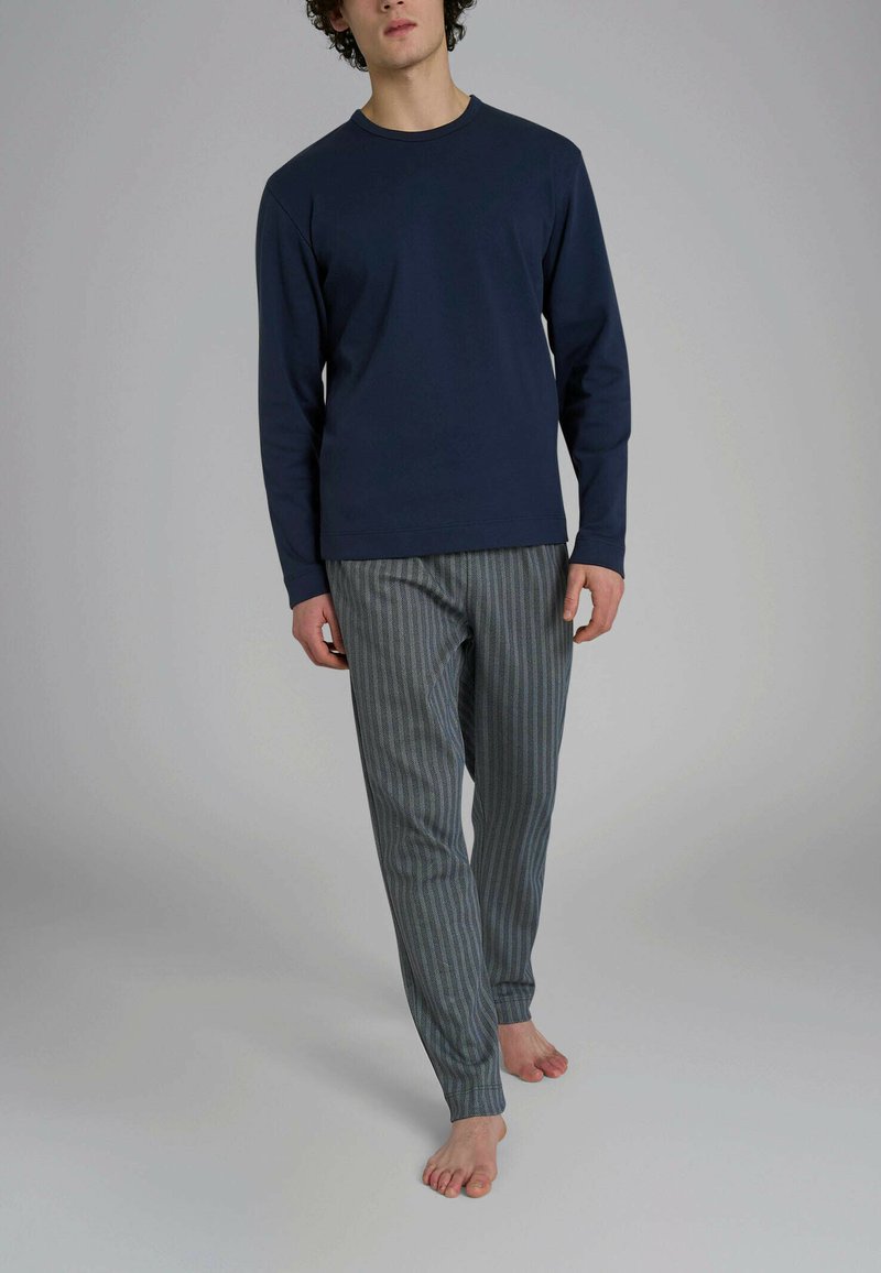 Camicia a maniche lunghe blu marina abbinata a pantaloni da pigiama grigi a righe; tessuto morbido, vestibilità comoda e sottile motivo verticale sui pantaloni.