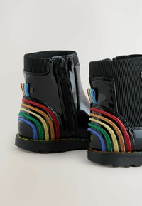 Svarta lackläderankelboots med ribbat krage, med färgglada broderade regnbågsränder och zipstängning på sidan.