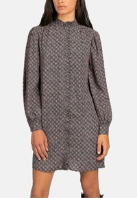 Vestido de manga larga en tela oscura con un estampado floral, cuello alto, cierre de botones en el frente y puños elásticos. Termina por encima de la rodilla.