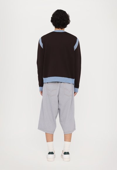 Brown sweatshirt with blue accents, ribbed cuffs, and hem. Light gray shorts with a relaxed fit and subtle stitching details.