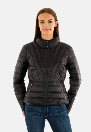 Veste noire isolée avec col haut, motif matelassé vertical, poches zippées et accents en matériel doré.
