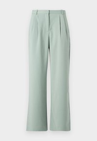 Pantalons larges vert clair avec plis, présentant une texture douce et une ceinture traditionnelle. Le tissu semble léger et doux.