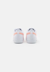 Sneakers bianchi con un design testurizzato, accentuato da dettagli rosa sul tallone e sui lati, una forma aerodinamica e suola in gomma.