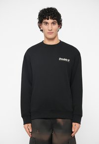 Μαύρο φούτερ με λαιμόκοψη, μακριά μανίκια και λευκό λογότυπο "Double V" στο αριστερό μέρος του στήθους. Διαθέτει ριμπ μανίκια και τελείωμα.