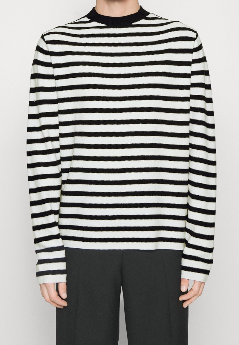 Svetr s černobílými pruhy, pletený, s klasickým kulatým výstřihem a dlouhými rukávy, s pravidelně rozloženými vodorovnými pruhy a žebrovanými manžetami.