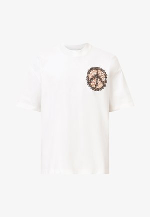 T-shirt en coton blanc avec un design de symbole de paix imprimé léopard sur la poitrine gauche, encadré par du texte noir en motif circulaire.