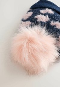 Navy blue knit winter hat with pink leopard print pattern and large fluffy light pink pom-pom on top, resting on white surface.
