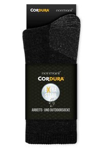 Schwarze Outdoor- und Arbeitssocken aus strapazierfähigem Cordura-Material. Mit gerippter Textur und verstärktem Zehenbereich. Verpackt mit einem Etikett.