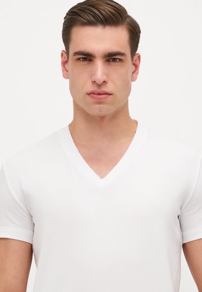 Weißes V-Ausschnitt-T-Shirt aus weicher Baumwolle. Klassische Kurzärmel, taillierte Passform, glatte Textur und minimale Markenkennzeichnung.