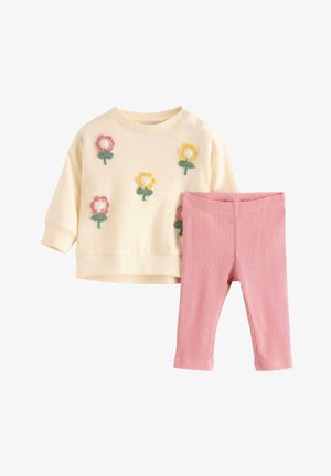 Kremfarvet babybluse med lange ærmer og applikationer af gule og pink blomster, parret med ribstrikkede pink leggings på hvid baggrund.