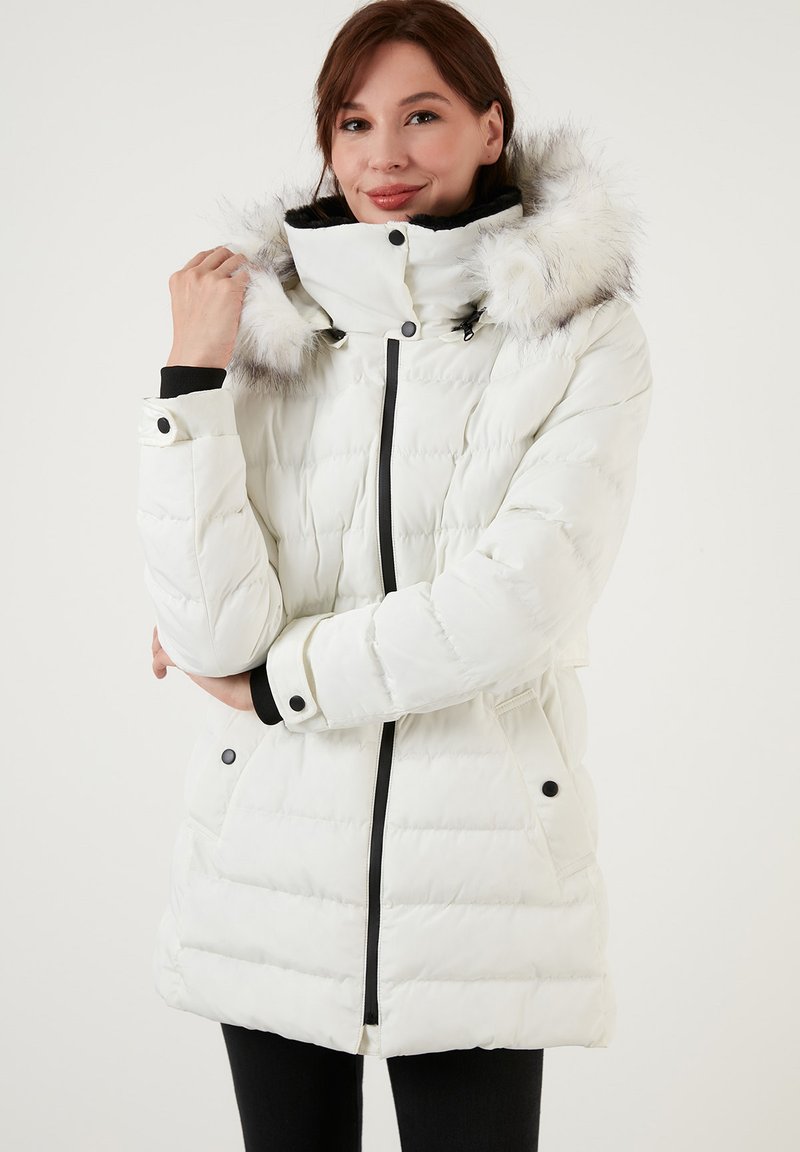 Veste matelassée blanche avec capuche en fausse fourrure, design capitonné, cordon de serrage ajustable, accents noirs et poches latérales pour plus de fonctionnalité.