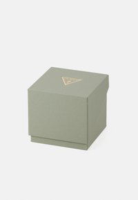 Žalia tekstūruota dovanų dėžutė su auksiniu trikampiu logotipu viršuje. Kvadratinė forma, su užlenkiamu dangčiu ir glotnia apdaila.