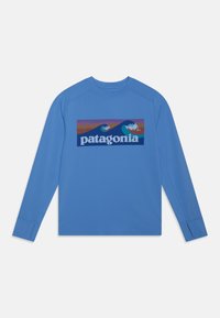 Långärmad blå skjorta tillverkad av ett mjukt tyg med en färgglad rektangulär grafik med vågor och berg, centrerad logotyptext.