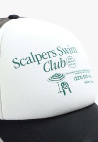 Căciulă de baseball albă și neagră cu text și ilustrații imprimate în verde. Are spate din plasă, margine curbată și detalii pentru Scalpers Swim Club.