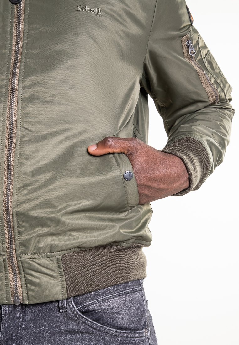 Veste bomber vert olive en nylon lisse, avec fermeture éclair à l'avant, poignets côtelés et une poche avec un détail de bouton-pression en métal.