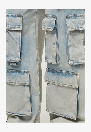 Vaaleansiniset cargo-housut, joissa on useita läpämääräisiä taskuja, kuluneet reunat ja hieman kulunut pinta. Materiaali on denim.