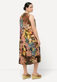 Vestido sin mangas con un vibrante patrón floral multicolor sobre un fondo verde oscuro. Presenta un diseño fluido y un dobladillo a la altura de la rodilla.