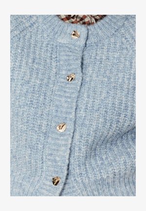 Cardigan tricoté bleu clair avec texture côtelée et boutons en forme de cœur dorés. Le col est rehaussé d'un motif à carreaux en dessous.